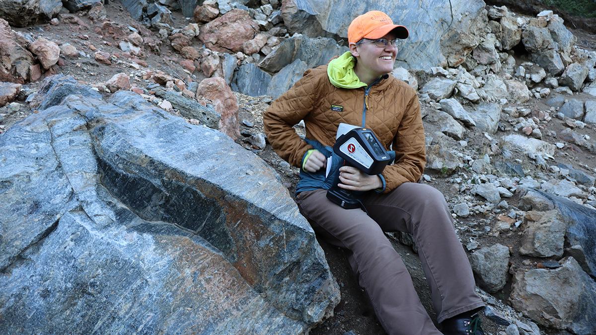 Erika Rader坐在俄勒冈州火山口湖的一堆岩石上.